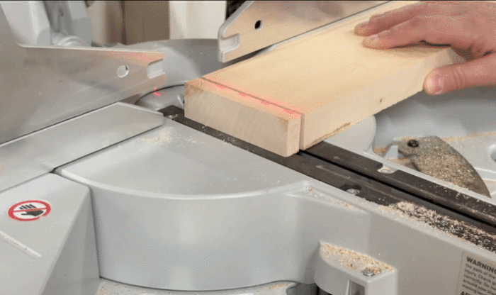 Amanda cuts a small section off the end of one board with a miter saw.