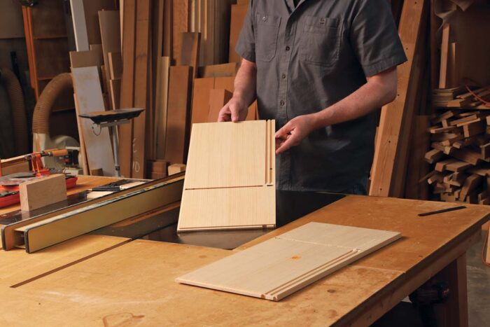 The author holds one of two pieces of wood showing precisely cut grooves in each.