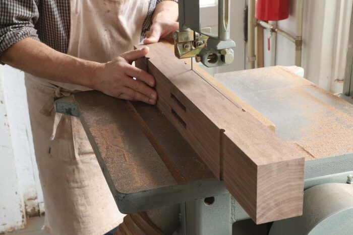 Tom uses a bandsaw to waste away the material between the two cove cuts, creating a lifted profile at the bottom of the foot. 