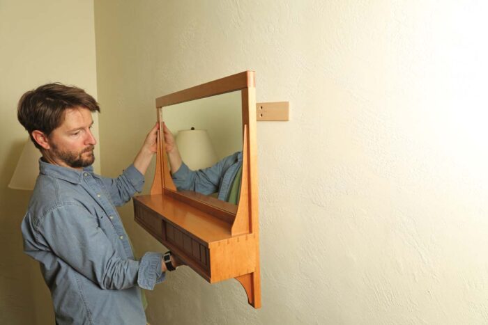 The assembled mirror being hung on the wall.