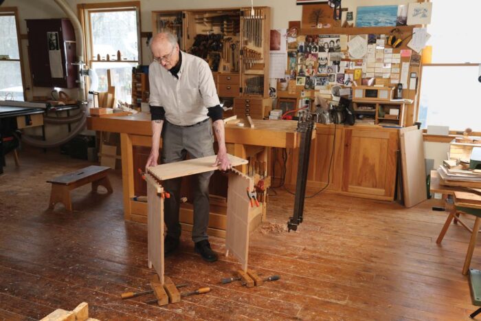 Chris uses wooden handscrew clamps to hold the sides vertically while he puts the top in place for glue up. 