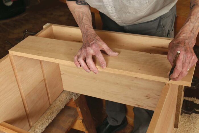 Chris marks the length of a board, using the case as a reference. This board will become dividers.