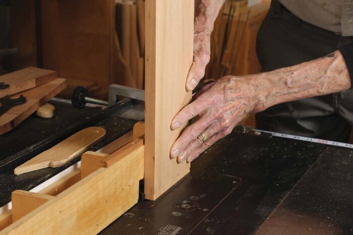 Chris holds a board vertically on the router table. 