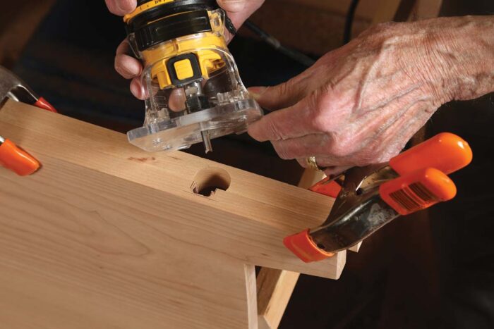 Chris uses a trim router to rout out waste on the sides of the chest, held together with spring clamps.