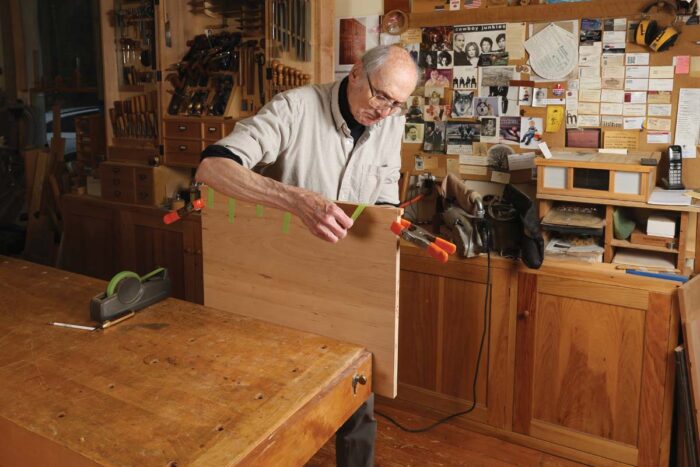 Chris glues a dovetailed strip to the panel that makes the shelf.