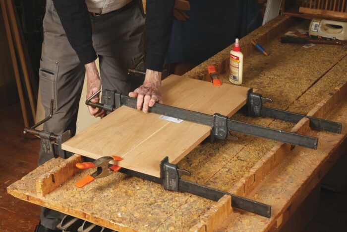 Chris clamps two cherry boards together, using spring clamps at either end to keep things flat.