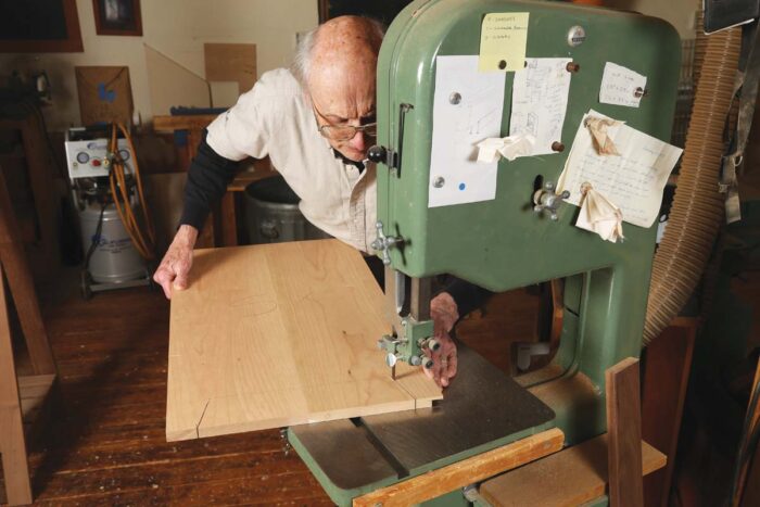 Chris uses the bandsaw to cut the bottom profile of the feet on the sides of the cabinet.