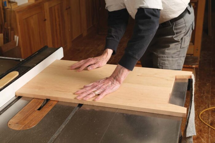 Chris uses a dado stack on the tablesaw to cut dadoes on the inside of the sides of the cabinet.