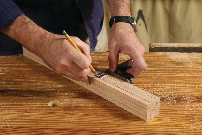 A combination square is being used to draw the lines down the side of the board.