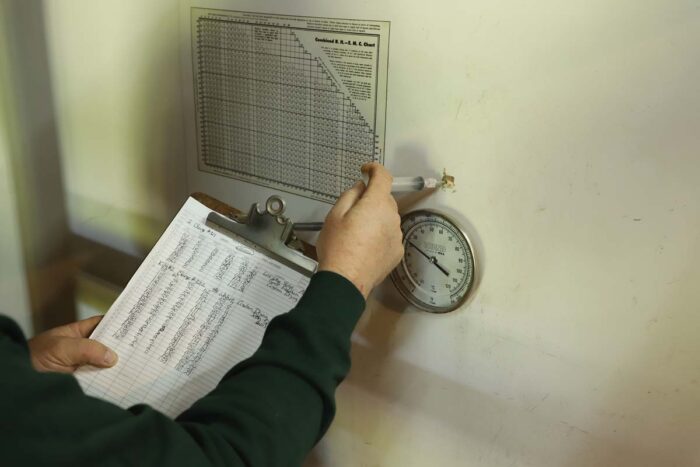 Someone checks a gauge on a kiln.