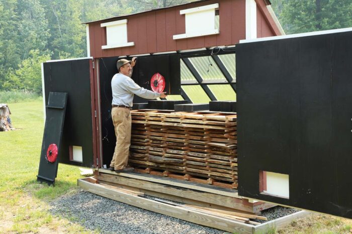 A sawyer standing in a solar kiln. 