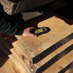 The moisture content of a board is being measured with a moisture meter.