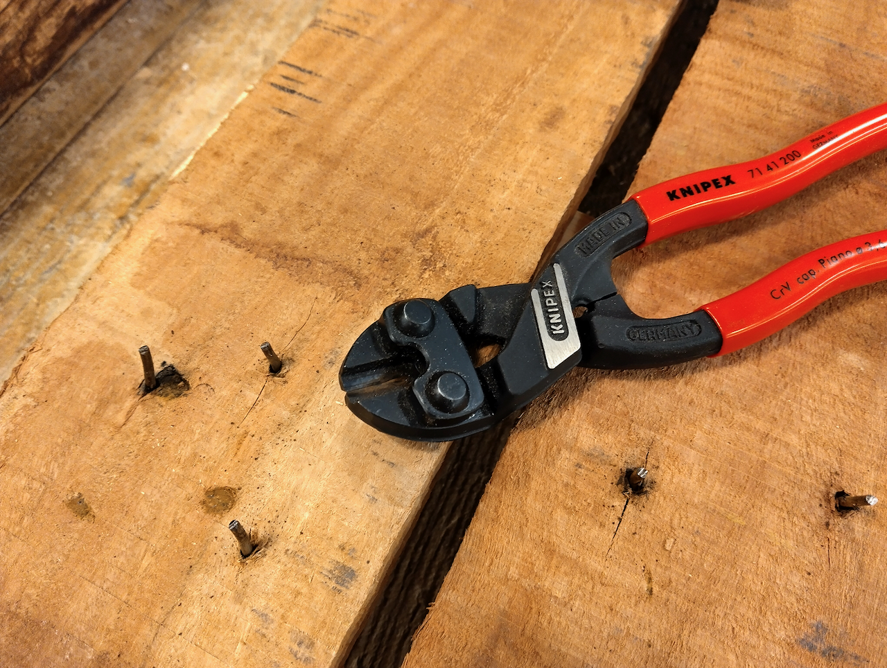 Nippers sitting on top of a reclaimed board with a bunch of exposed nails clipped to 1/2" long. 