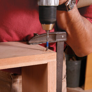 Clearance hole next. Drill into the pilot hole, using a bit just larger than the screw’s thread diameter. A depth stop or gauge (in this case, tape) prevents drilling into the bottom board.