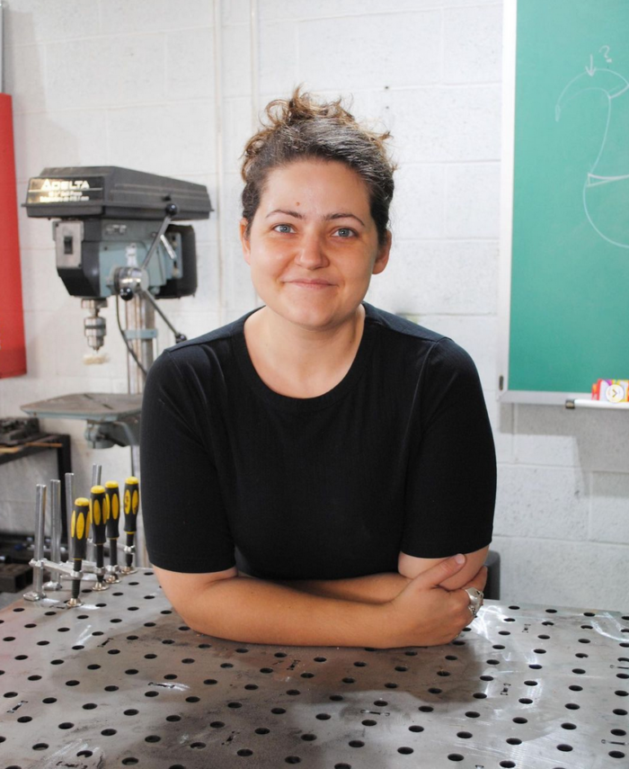 A photo of Sophie standing at a welding table. 